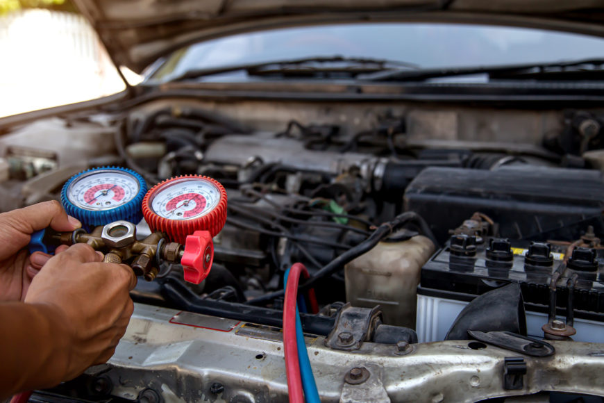 Auto mechanic using measuring equipment tool for filling car air conditioners fix checking. Concepts of Old car Repair service and insurance.